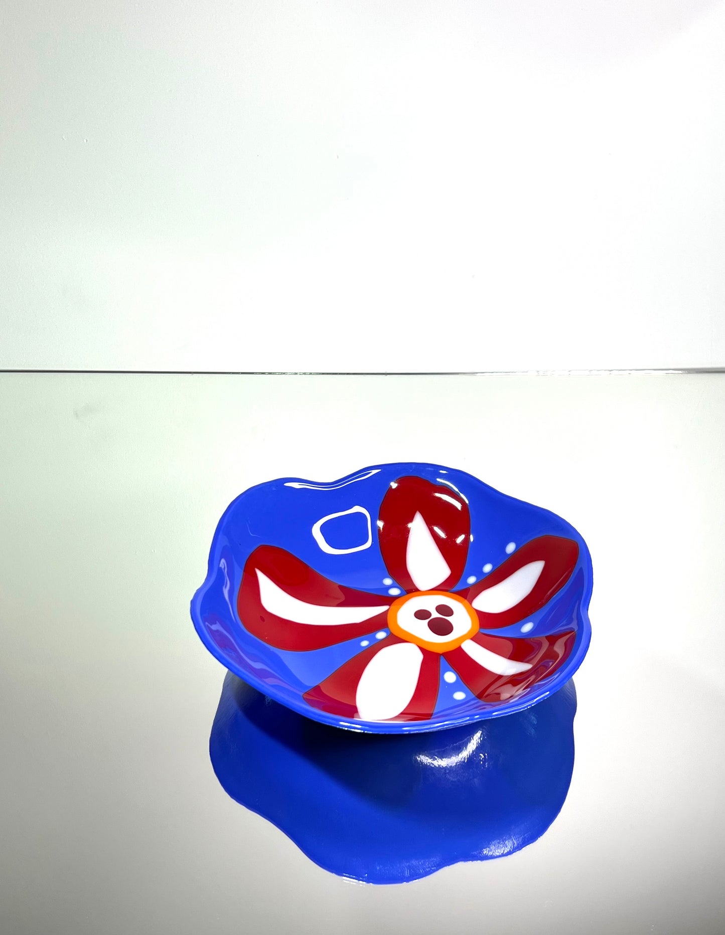 Blue glass bowl with red and white flower