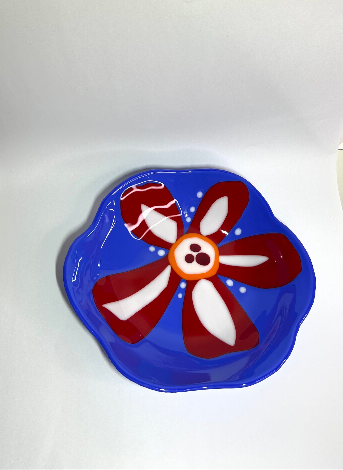 Blue glass bowl with red and white flower